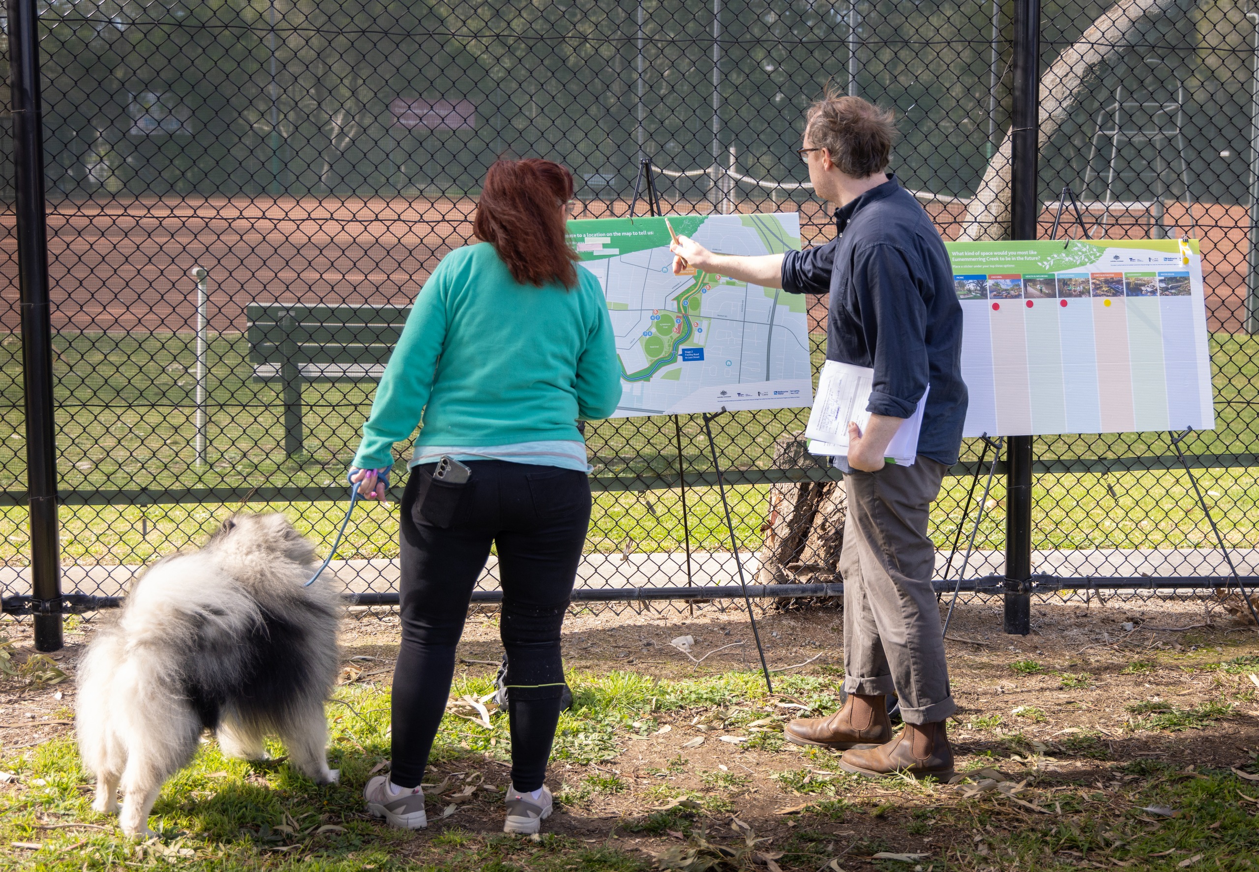 Photo of community member providing feedback looking at project map on display. 