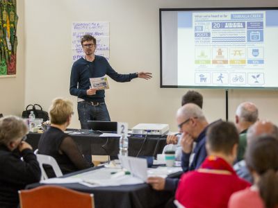 Man presenting concept design to seated Community Advisory Group members